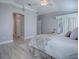 Bright main bedroom featuring light wood floors, neutral paint, ceiling fan, and sliding glass doors with natural light at 7812 Se 167Th Mistwood Ln, The Villages, FL 32162
