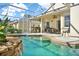 Inviting backyard pool with waterfall feature, seating areas, and screened enclosure at 995 Hidden Blf, Clermont, FL 34711