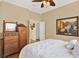 Cozy bedroom with wood floors features white bedding, antique dresser, and decor at 995 Hidden Blf, Clermont, FL 34711