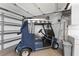 Close-up of a golf cart parked in garage with storage and electrical outlets at 1202 San Bernardo Rd, The Villages, FL 32162