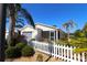 Well-maintained single-story home with a white picket fence and lush tropical landscaping at 1215 Eagle Ridge Dr, The Villages, FL 32162