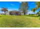 Expansive backyard featuring a screened patio, lush lawn, and mature trees under a sunny sky at 12225 Se 173Rd Pl, Summerfield,, FL 34491