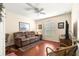 Cozy bedroom with hardwood floors, a brown sofa, and a ceiling fan providing a comfortable living space at 12225 Se 173Rd Pl, Summerfield,, FL 34491