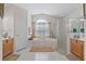 Bright bathroom featuring a soaking tub, glass enclosed shower, and double vanity sinks at 12626 Douglas Fir Ct, Clermont, FL 34711