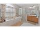 Bright bathroom featuring a soaking tub, glass enclosed shower, and white tiled floors at 12626 Douglas Fir Ct, Clermont, FL 34711