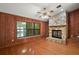 Cozy living room with a stone fireplace, wood paneling, and a large window offering scenic views at 1322 Howard Rd, Leesburg, FL 34748