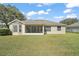 View of the home's screened-in lanai and bay window from the large, green backyard at 13800 Wellington Ln, Grand Island, FL 32735