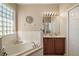 Bright bathroom featuring a soaking tub, glass block window, and a vanity with dark wood cabinets at 13800 Wellington Ln, Grand Island, FL 32735