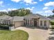 Charming single-story home with stone accents, a three-car garage and a circular driveway at 13800 Wellington Ln, Grand Island, FL 32735