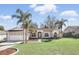 Well-maintained single-story home featuring a manicured lawn, palm trees, and attached garage at 15912 Lake Orienta Ct, Clermont, FL 34711