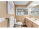 Well-lit bathroom featuring a toilet, a sink with cabinets, and a window at 16011 Acorn Cir, Tavares, FL 32778