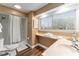 Bright bathroom with tub, a large window with blinds, and a sink with storage at 16011 Acorn Cir, Tavares, FL 32778