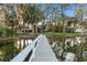Scenic view of a lake with a long wooden dock leading to a gazebo and boat house at 16011 Acorn Cir, Tavares, FL 32778