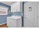 This laundry room features a washer, dryer, white cabinets, blue walls, and wood flooring at 16801 Se 74 Soulliere Ave, The Villages, FL 32162