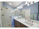 Bathroom vanity with dual sinks, a glass-enclosed shower, and blue walls at 1781 Kingfisher Ct, The Villages, FL 32162