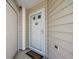 Close-up of a white front door with a glass window, set against tan siding, and a welcome mat at 1781 Kingfisher Ct, The Villages, FL 32162