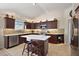 Modern kitchen featuring dark wood cabinetry, stainless steel appliances, and a large island with seating at 1781 Kingfisher Ct, The Villages, FL 32162