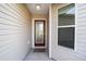 Close-up of the front door, featuring a decorative glass window and neutral siding at 2046 Dalecroft Trl, The Villages, FL 32162