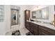 Bathroom with granite countertop, dark wood cabinetry, decorative mirror, and glass block window at 2050 Biller Cir, The Villages, FL 32163