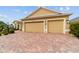 Spacious three-car garage with a brick paver driveway and well-maintained landscaping at 2050 Biller Cir, The Villages, FL 32163