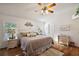 Bright main bedroom with hardwood floors, ceiling fan, white trim, and beach-themed decor at 2114 Gerardo Ave, The Villages, FL 32159