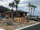 View of the brick clubhouse with palm trees and a landscaped area with a variety of decorative yard ornaments at 22 Big Tree Dr, Fruitland Park, FL 34731