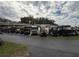 View of multiple golf carts parked at the community with a low building in the background and a cloudy sky at 22 Big Tree Dr, Fruitland Park, FL 34731