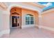 Elegant front entrance featuring a decorative wood door, arched transom window, and neutral stucco at 2311 Bramble Ter, The Villages, FL 32162