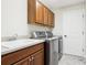 Laundry room featuring washer, dryer, sink, wood cabinets, and tile flooring at 2311 Bramble Ter, The Villages, FL 32162