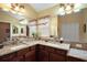 Bathroom with double sink vanity with granite counters, framed mirrors and decorative lighting at 2360 Unity Ter, The Villages, FL 32162