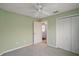 A neutral-colored bedroom with a ceiling fan and a door to the main entry hallway and closet with double doors at 2360 Unity Ter, The Villages, FL 32162