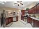 Modern kitchen featuring dark wood cabinetry, granite countertops, stainless steel appliances, and tile flooring at 2360 Unity Ter, The Villages, FL 32162