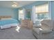 Comfortable blue bedroom with natural light, dresser, and a cozy armchair at 26315 Newcombe Cir, Leesburg, FL 34748