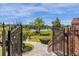 Landscaped walkway through an ornate gate leading to a serene lake view at 27852 Lake Jem Rd, Mount Dora, FL 32757