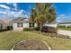 Charming single-story home featuring a well-manicured lawn and mature landscaping with a large palm tree at 3009 Batally Ct, The Villages, FL 32162