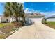 Single-story home boasts a spacious driveway, well-maintained lawn, and lush landscaping with a large palm tree at 3009 Batally Ct, The Villages, FL 32162