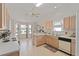 Spacious kitchen featuring light wood cabinets, a double sink with window, and white appliances and tile floors at 3009 Batally Ct, The Villages, FL 32162