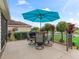 An outdoor dining area is shaded by a vibrant blue umbrella, complemented by lush landscaping at 3047 Bevill Ln, The Villages, FL 32163