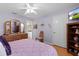 Cozy bedroom with light purple walls, ceiling fan, wood floors, and ensuite bathroom at 3056 Saint Thomas Ln, The Villages, FL 32162