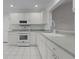 Bright kitchen features white cabinets, appliances, and tile floors for a clean, modern look at 3056 Saint Thomas Ln, The Villages, FL 32162