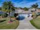 Aerial view of a well-maintained home with a manicured lawn, lush landscaping and a three-car garage at 3142 Islawild Way, The Villages, FL 32163