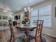 Dining area with a round table, four chairs, plantation shutters, and wood floors overlooking the living room at 3142 Islawild Way, The Villages, FL 32163