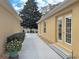 Side exterior view of home featuring a walkway, mature landscaping, and double doors at 3285 Archer Ave, The Villages, FL 32162