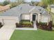 Aerial view of a charming single-story home featuring a lush green lawn and mature landscaping at 3435 Tumbling River Dr, Clermont, FL 34711