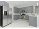 Modern kitchen with gray cabinets, stainless steel appliances, and white marble floors at 3435 Tumbling River Dr, Clermont, FL 34711