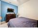 Bright bedroom featuring a dark wood dresser under a wall-mounted TV with blue accent wall paint at 3449 Meadow Beauty Way, Clermont, FL 34714