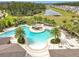 Stunning aerial view of the community pool area with sun loungers, tables, umbrellas, and beautiful palm trees at 3449 Meadow Beauty Way, Clermont, FL 34714