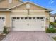 Well-kept two-car garage with a charming exterior and brick driveway at 3449 Meadow Beauty Way, Clermont, FL 34714