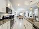 Well-lit kitchen featuring stainless steel appliances, granite countertops, and white cabinetry, flowing into the dining area at 3449 Meadow Beauty Way, Clermont, FL 34714