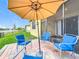 Inviting outdoor patio with umbrella, blue chairs, and a scenic view of the nearby lake at 3449 Meadow Beauty Way, Clermont, FL 34714